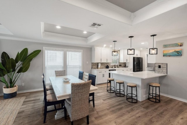 dining area with crown molding, sink, and a tray ceiling