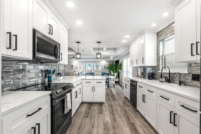 kitchen with sink, decorative light fixtures, black appliances, kitchen peninsula, and white cabinets