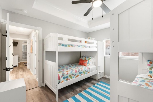 bedroom featuring a tray ceiling, dark wood-type flooring, and ceiling fan