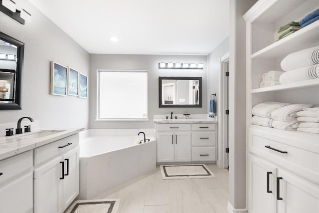 13569 Bullion Ct, Corpus Christi, TX 78418 - full bathroom with two vanities, a garden tub, marble look tiles, and recessed lighting