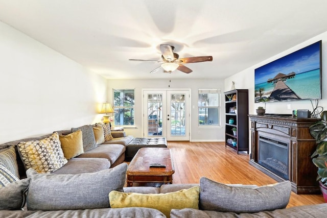 living room featuring french doors, a fireplace, wood finished floors, and a ceiling fan