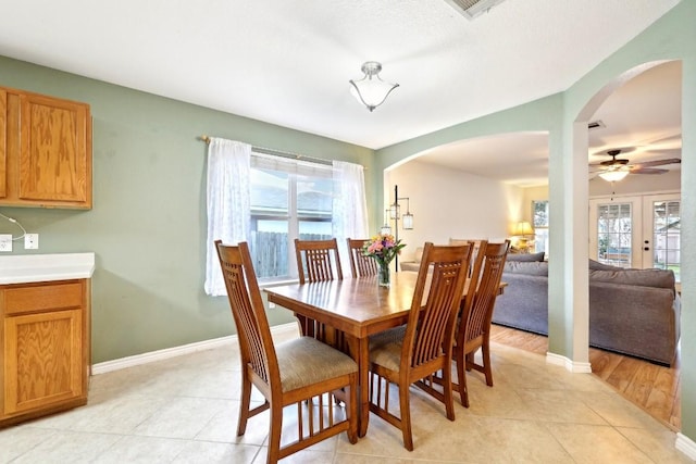 dining room with baseboards, arched walkways, a wealth of natural light, and light tile patterned flooring