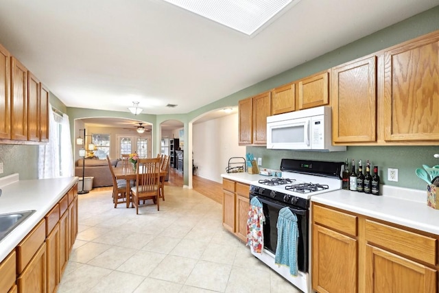 kitchen featuring gas stove, light countertops, arched walkways, and white microwave