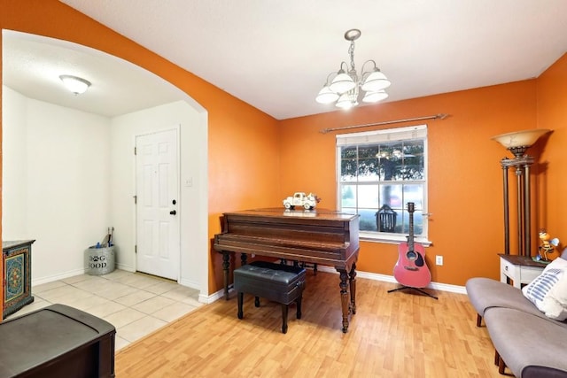 living area with arched walkways, light wood-type flooring, and baseboards