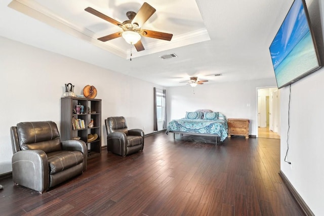 bedroom with ceiling fan, wood finished floors, visible vents, a raised ceiling, and crown molding