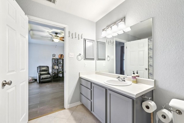 bathroom featuring ceiling fan, a textured wall, toilet, vanity, and tile patterned floors