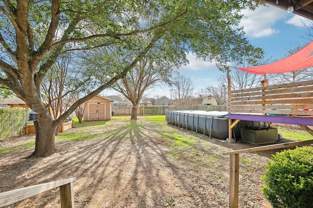 view of yard featuring a storage shed, a fenced backyard, a fenced in pool, and an outdoor structure