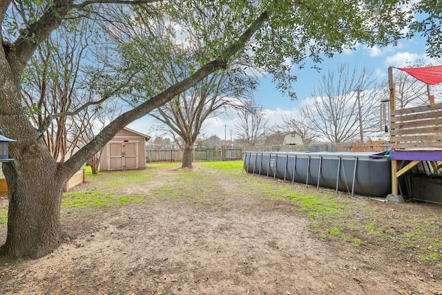 view of yard featuring a storage shed, fence, an outdoor pool, and an outdoor structure