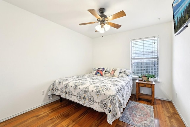 bedroom with wood finished floors, a ceiling fan, and baseboards