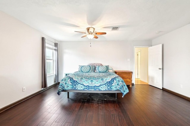 bedroom with a ceiling fan, visible vents, baseboards, and hardwood / wood-style flooring