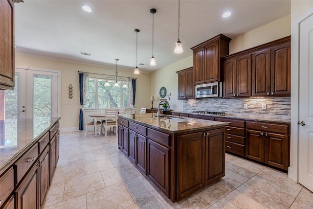 kitchen with tasteful backsplash, visible vents, appliances with stainless steel finishes, stone countertops, and a sink