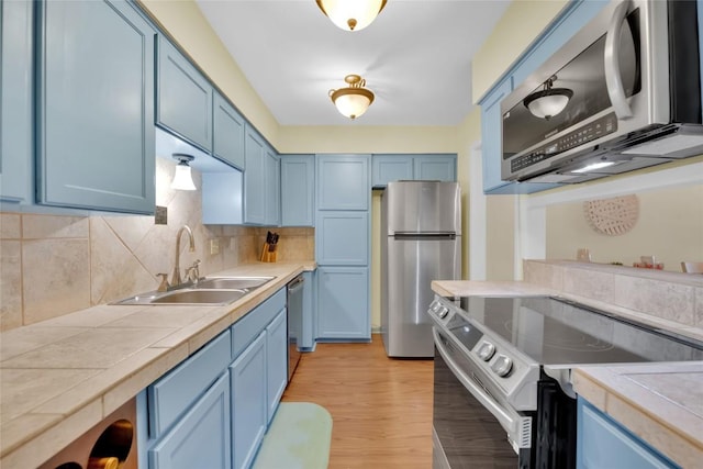 kitchen featuring stainless steel appliances, sink, and blue cabinetry