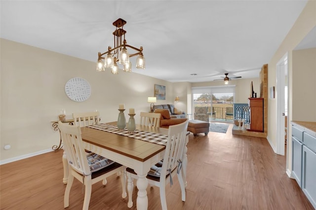 dining room with ceiling fan with notable chandelier and light hardwood / wood-style flooring