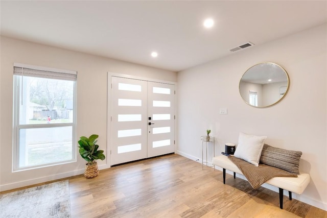 entryway featuring light wood-type flooring, french doors, and a healthy amount of sunlight