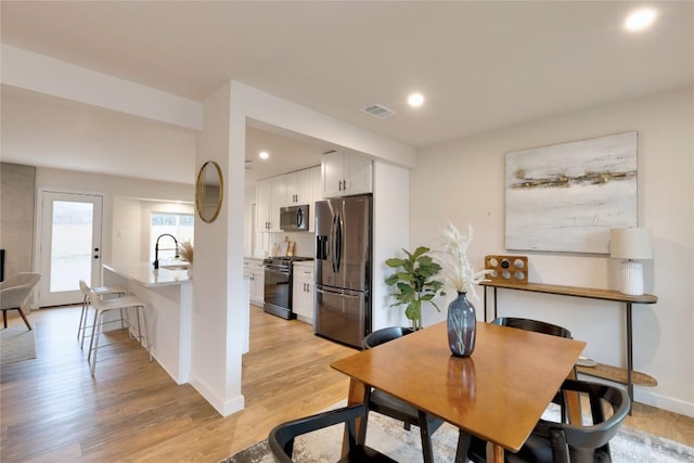 dining room featuring sink and light hardwood / wood-style floors