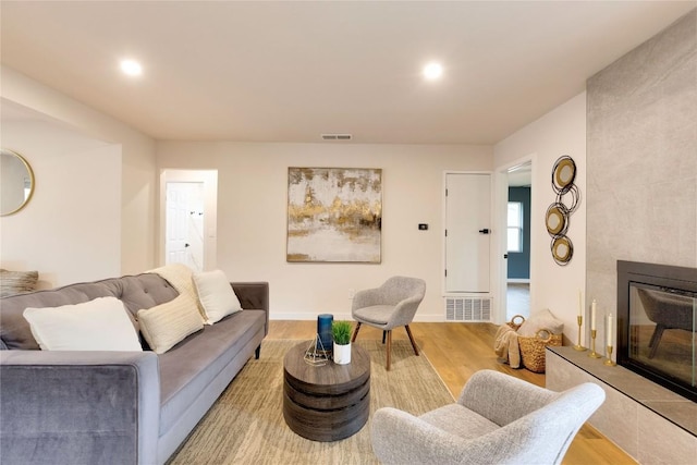 living room featuring a tiled fireplace and light hardwood / wood-style flooring