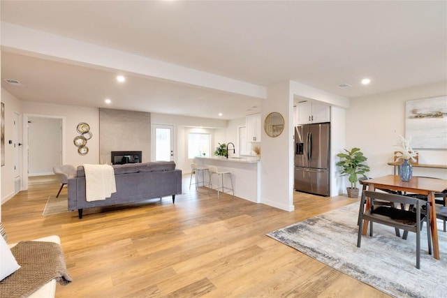 living room with a fireplace, sink, and light hardwood / wood-style flooring