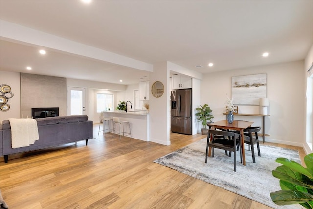 dining space featuring light wood-type flooring, sink, and a large fireplace