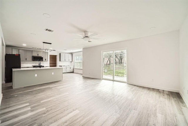 unfurnished living room featuring ceiling fan and light wood-type flooring