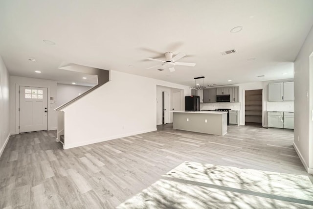 unfurnished living room with ceiling fan and light wood-type flooring