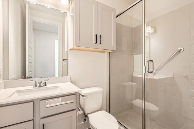 bathroom with vanity, toilet, and a shower with door