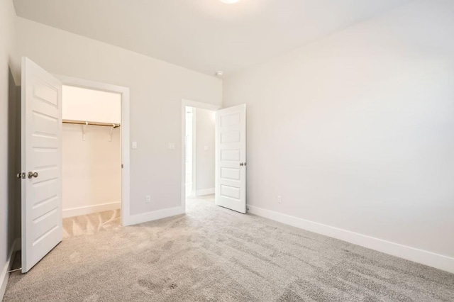 unfurnished bedroom featuring a spacious closet, carpet floors, and a closet