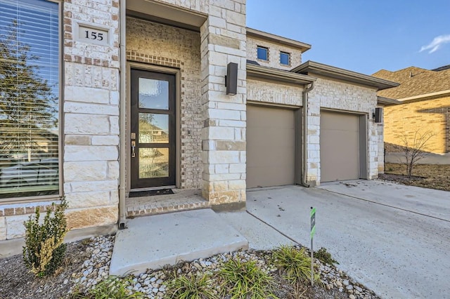155 Cyrus Milton Dr, Buda, TX 78610 - view of exterior entry with stone siding, concrete driveway, and a garage