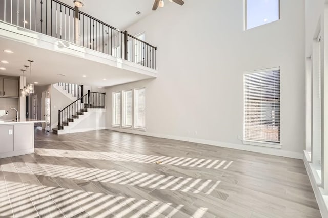 155 Cyrus Milton Dr, Buda, TX 78610 - unfurnished living room featuring a high ceiling, a ceiling fan, stairway, baseboards, and a sink