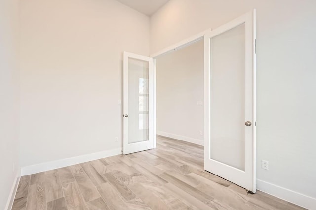 unfurnished room featuring french doors and light hardwood / wood-style flooring