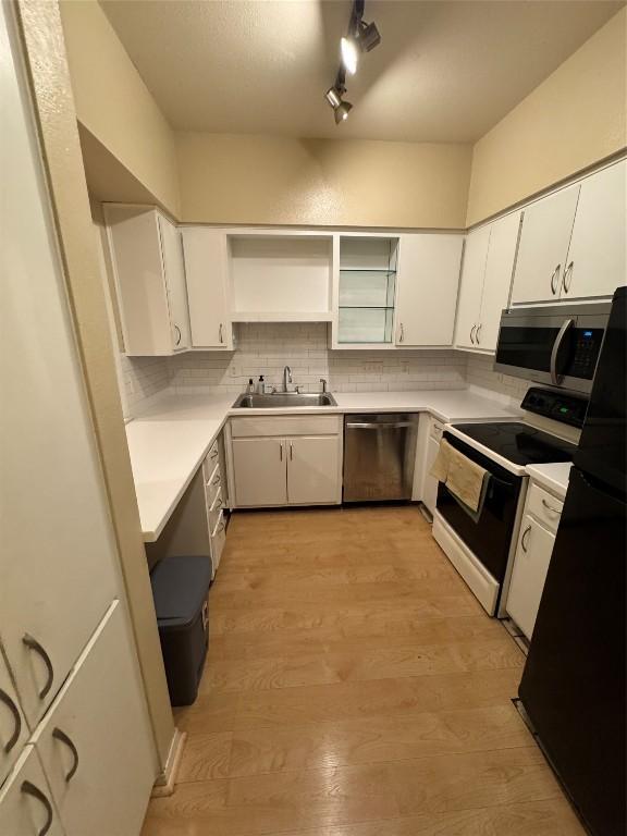 kitchen with sink, white cabinetry, tasteful backsplash, light hardwood / wood-style flooring, and stainless steel appliances