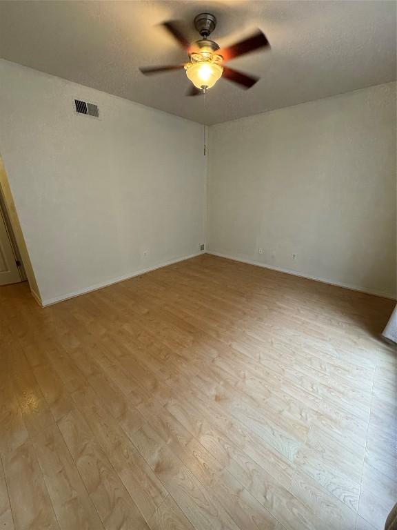 empty room featuring ceiling fan, light hardwood / wood-style floors, and a textured ceiling