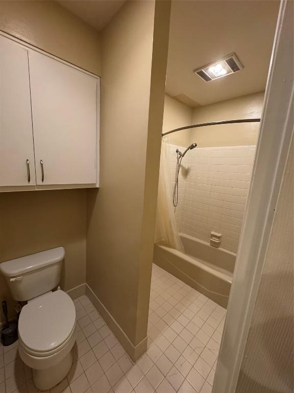 bathroom featuring shower / tub combo with curtain, tile patterned floors, and toilet