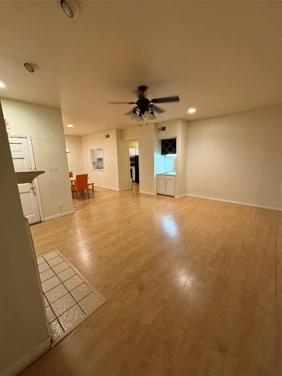 unfurnished living room featuring ceiling fan and light hardwood / wood-style flooring