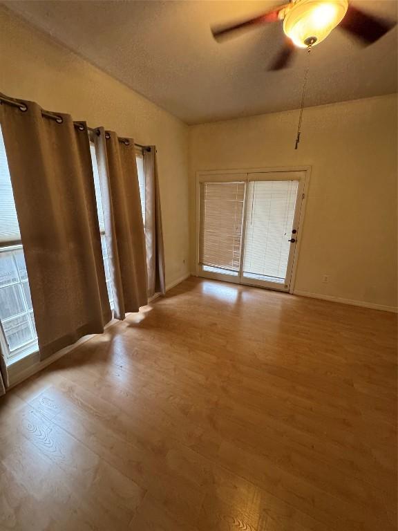 empty room featuring a wealth of natural light, hardwood / wood-style floors, a textured ceiling, and ceiling fan