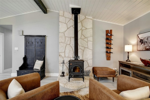 living room with lofted ceiling with beams, a wood stove, wood ceiling, and light wood-type flooring