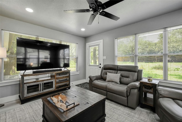 living room featuring ceiling fan and a textured ceiling