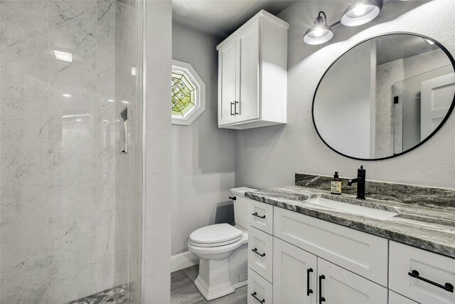 bathroom with vanity, toilet, and a tile shower