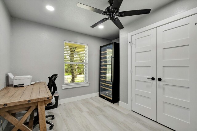 office area featuring wine cooler, ceiling fan, and light wood-type flooring