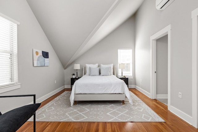 bedroom featuring wood-type flooring, lofted ceiling, and a wall unit AC