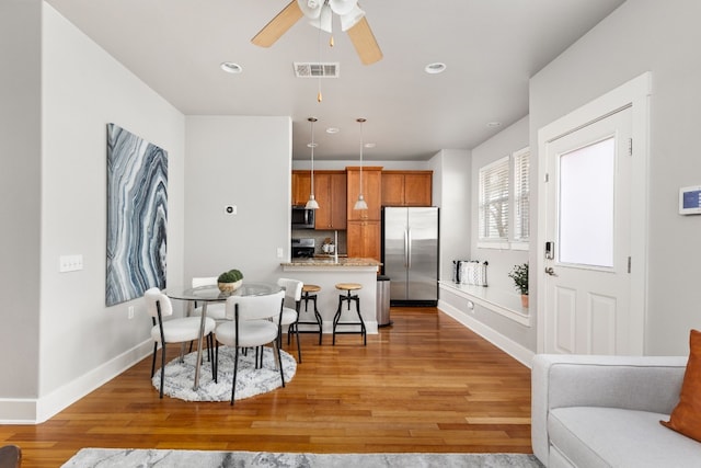 dining space with ceiling fan and light wood-type flooring