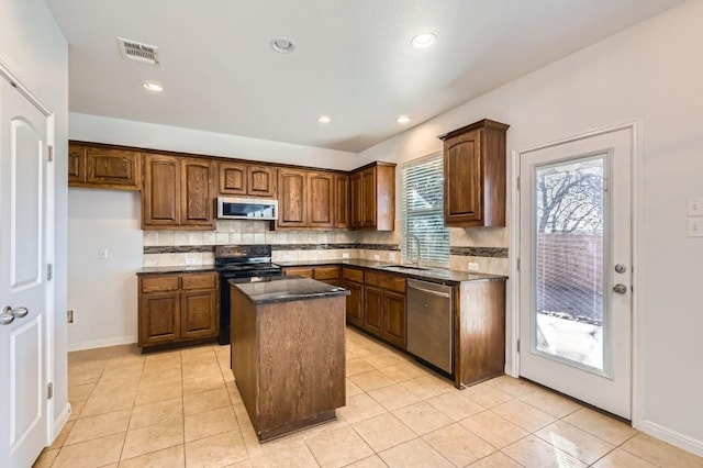 kitchen featuring tasteful backsplash, stainless steel appliances, a center island, and sink