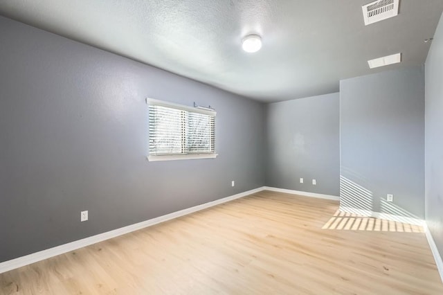 empty room with a textured ceiling and light hardwood / wood-style floors