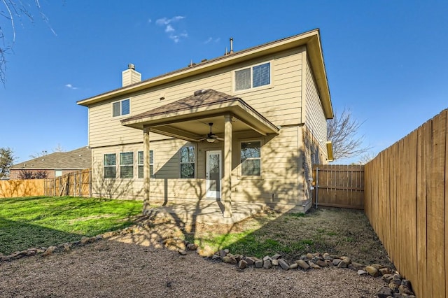 back of house featuring ceiling fan and a yard