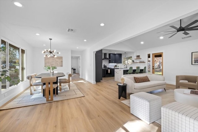 living room featuring ceiling fan with notable chandelier and light hardwood / wood-style flooring