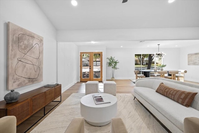 living room with lofted ceiling, hardwood / wood-style flooring, french doors, and a chandelier