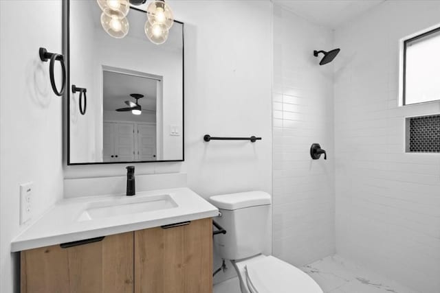 bathroom featuring vanity, a tile shower, and toilet