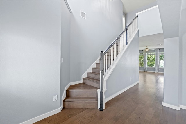 stairway with hardwood / wood-style flooring, ceiling fan, and a high ceiling