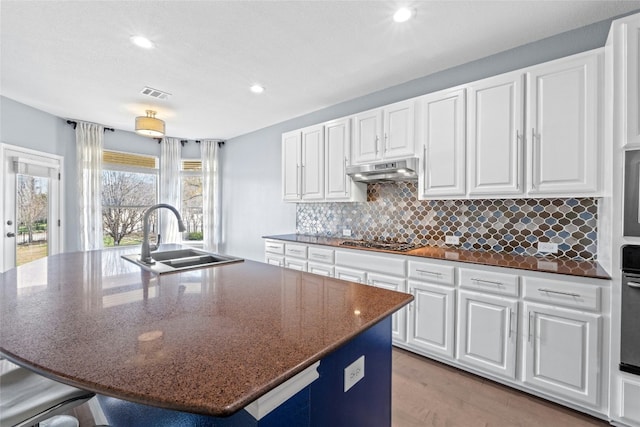 kitchen featuring an island with sink, sink, dark stone countertops, white cabinets, and stainless steel appliances