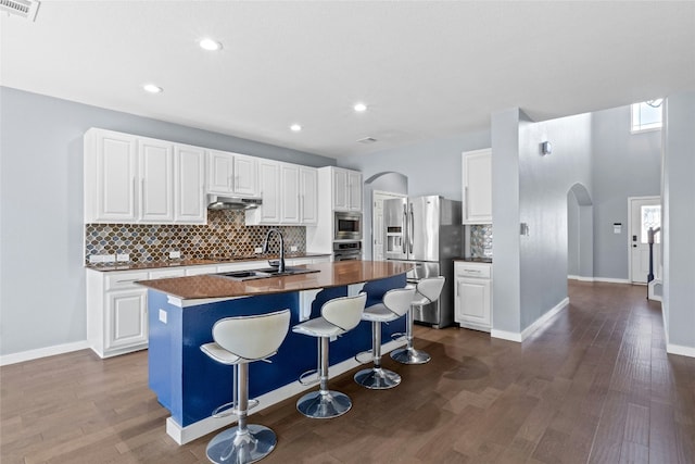 kitchen featuring sink, a breakfast bar, appliances with stainless steel finishes, white cabinets, and a center island with sink