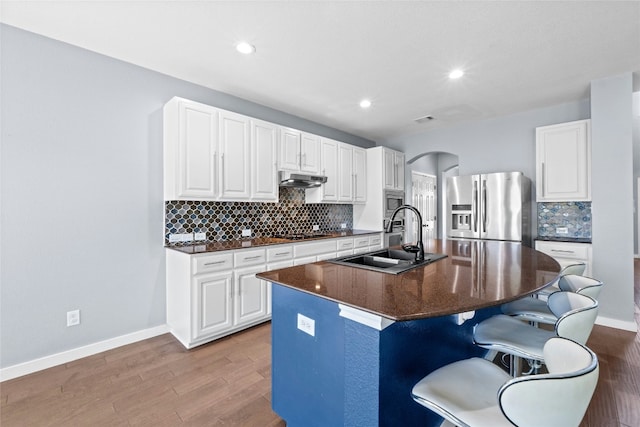 kitchen with appliances with stainless steel finishes, white cabinetry, sink, a breakfast bar area, and a kitchen island with sink